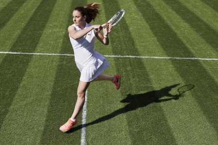 Woman playing tennis on grass court.